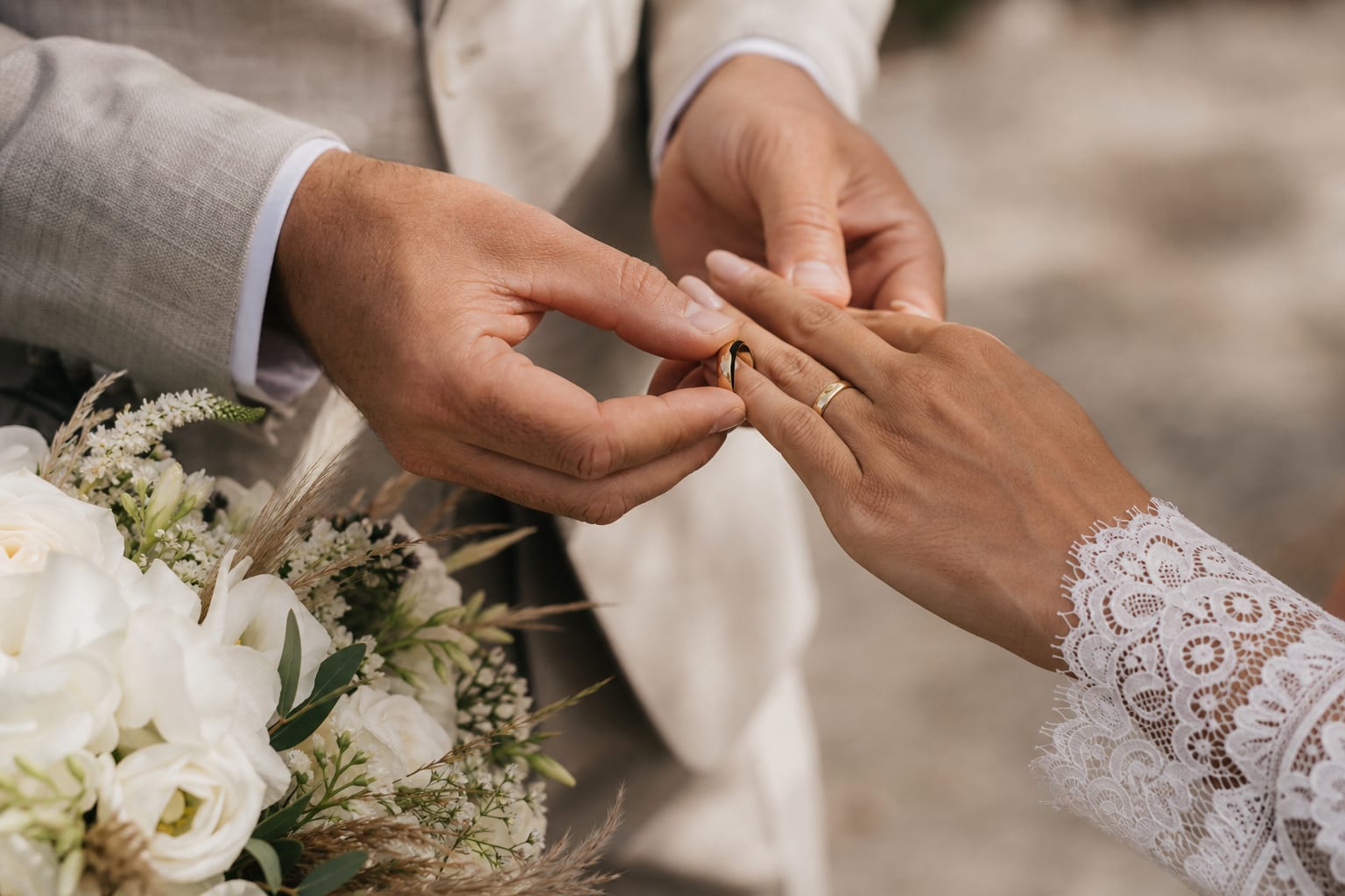 兩人交換結婚戒指的特寫,身旁放著白色捧花